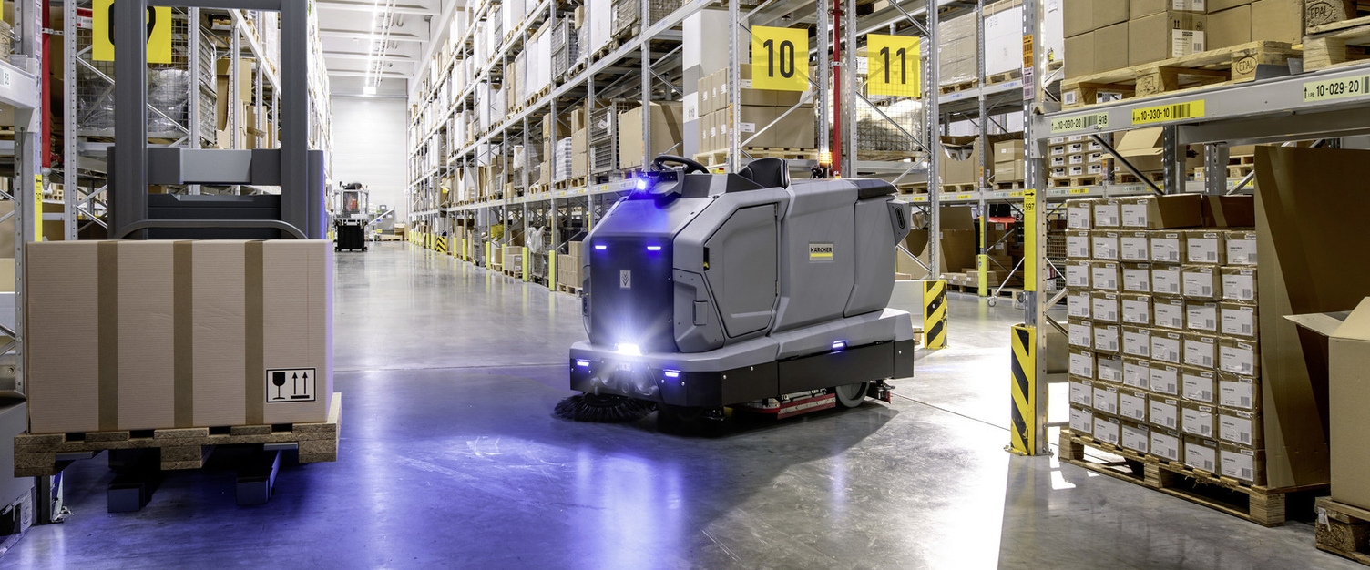 Ein autonomer Kärcher KIRA B 200 Reinigungsroboter  im Einsatz zur Bodenreinigung in einem weitläufigen Hochregallager.