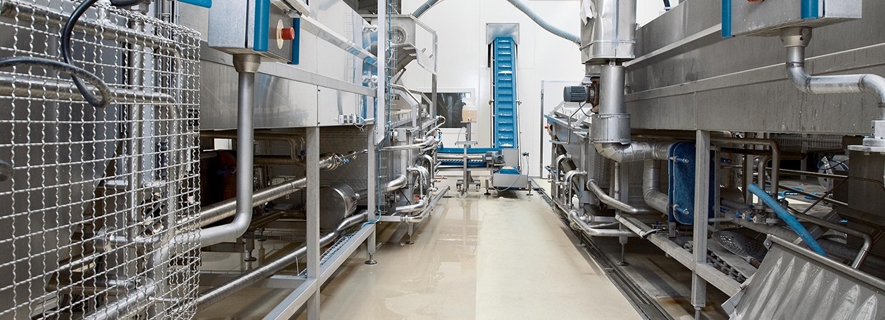 Effizienz in der Lebensmittelindustrie Hygienische Reinigung einer industriellen Lebensmittelproduktionsanlage mit modernen Edelstahl-Maschinen und nassen Böden – professionelle Systemlösungen von Kärcher für höchste Sauberkeitsstandards.