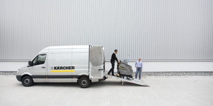 Ein Kärcher Service-Fahrzeug mit einer Verlanderampe, über die eine professionelle Scheuersaugmaschine