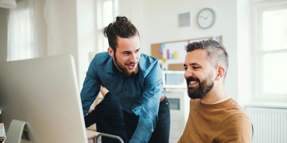 Kärcher Newsletter abonnieren Zwei Kollegen in einem modernen Büro betrachten gemeinsam den Kärcher Newsletter am Computerbildschirm