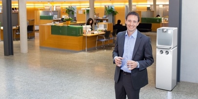 Kärcher Wasserspender für Behörden Ein Mann im Business-Outfit steht in einem weitläufigen, modernen Foyer einer öffentlichen Einrichtung