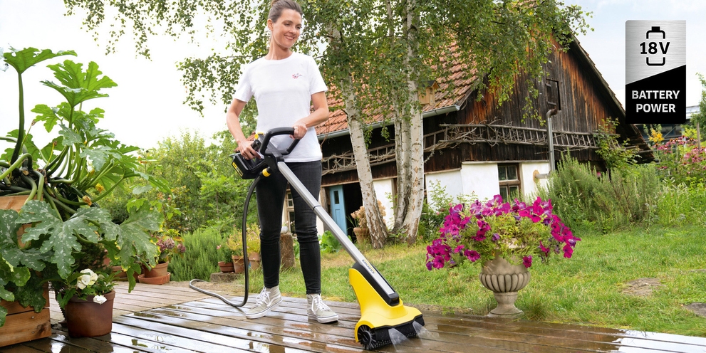 Kärcher Akku-Terrassenreiniger Eine Frau reinigt eine Holzterrasse mit dem Kärcher Akku-Terrassenreiniger