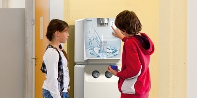 Kärcher Wasserspender mit individuellem Design & Firmen-CI Zwei Anwender zapfen Wasser an einem Kärcher Wasserspender mit individualisiertem Frontdesign.