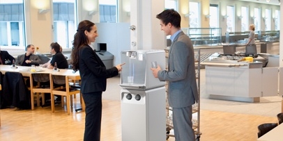 Effiziente Wasserentnahme in Kärcher Zwei Personen in einem modern gestalteten Restaurant- oder Kantinenbereich bedienen einen Kärcher Wasserspender