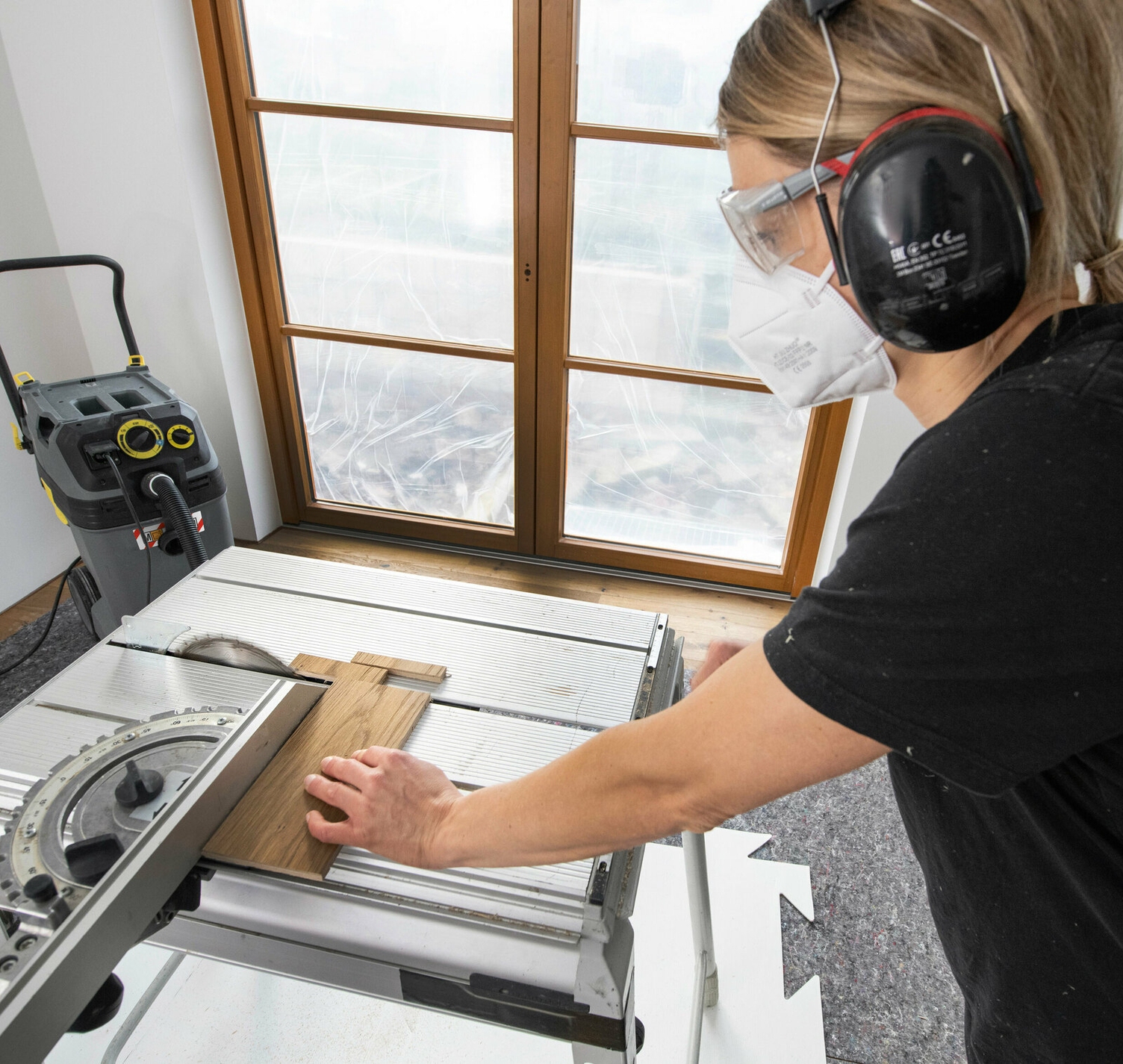 Bij het zagen van hout onstaan spanen en stof Een persoon zaagt hout met behulp van een machine