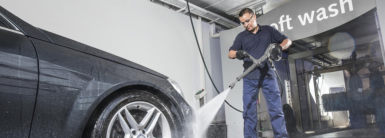 Carwash hogedrukreiniger Man gebruikt hogedrukreiniger om auto af te spoelen alvorens het de wasstraat inrijdt