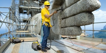 Efficiënte reiniging met een oppervlakteprestatie van 15 m² per uur Een medewerker straalt de binnenzijde van de hand van het Christusbeeld op de Corcovado.