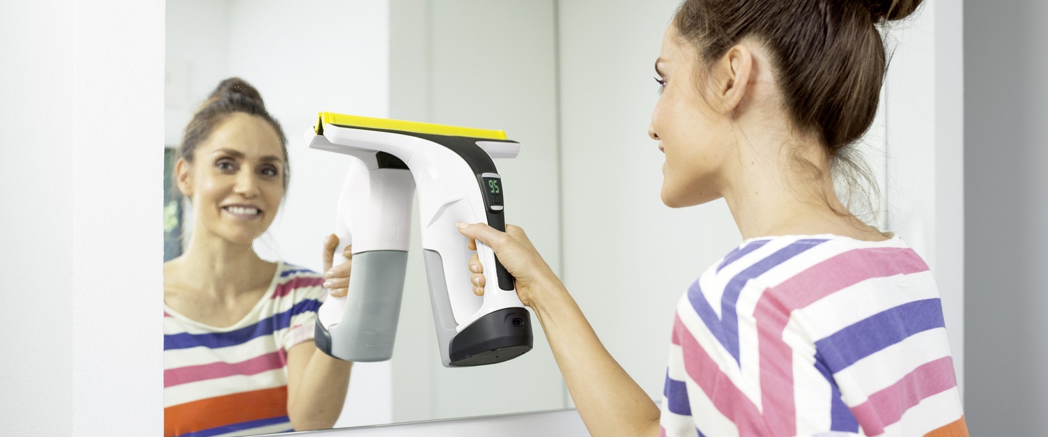 Nettoyage des miroirs Femme nettoyant un miroir avec l'aspirateur nettoyeur de vitres Kärcher