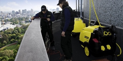 Opstelling van de apparatuur op de middelste omloop voor de watertoevoer naar de klimmers Technici stellen gele Kärcher-warmwater-hogedrukreinigers op het uitzichtplatform van de Euromast op.
