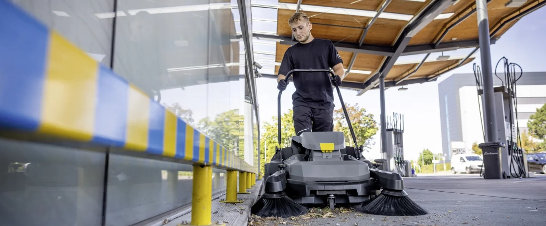Men gebruikt hangeleide veegmachine om bladeren van de grond te vegen