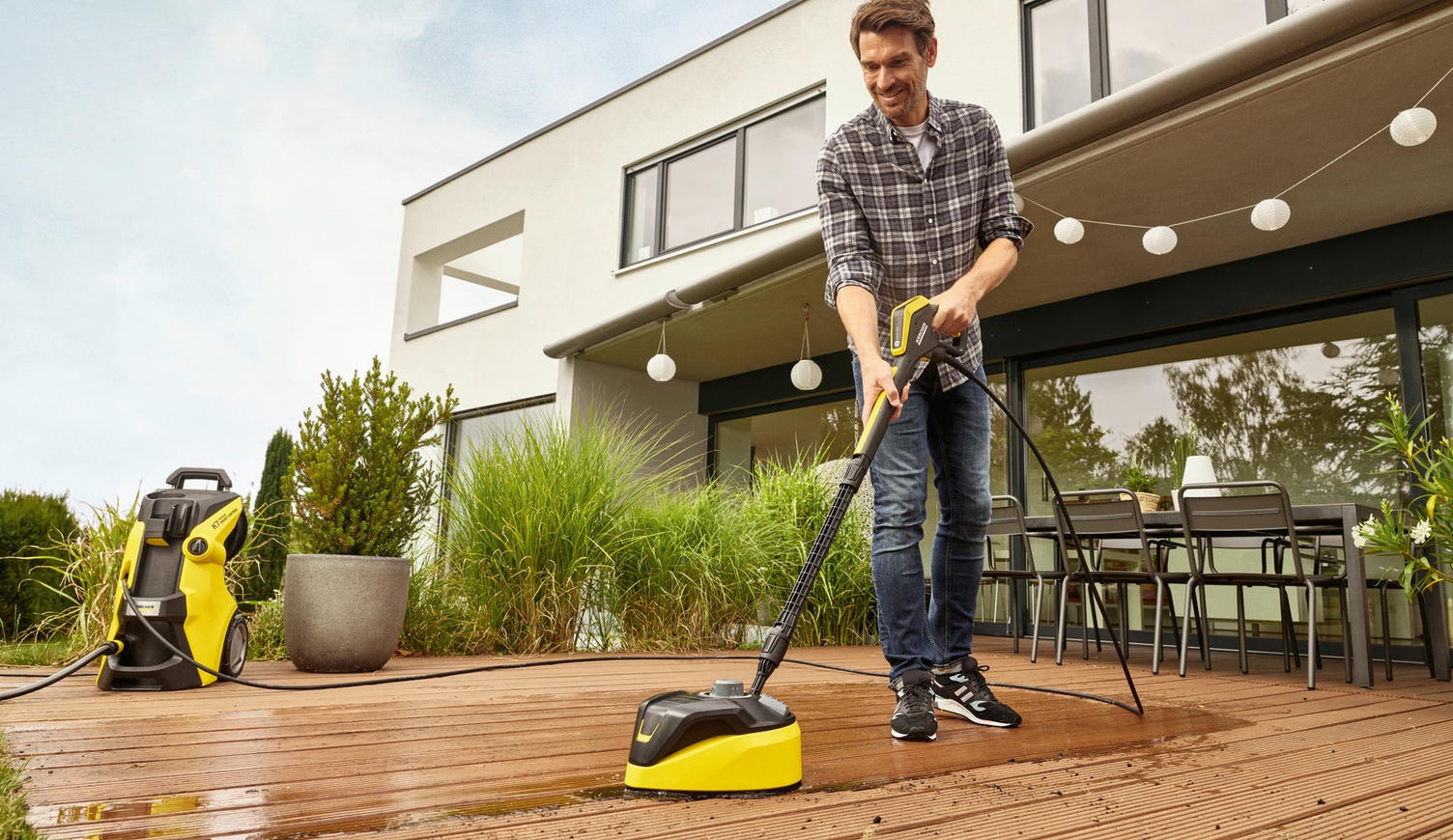 Een houten terras schoonmaken Man poetst zijn houten terras