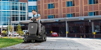 Kärcher veegmachine voor gebouw Kärcher zitveegmachine KM 90/60 veegt voor de ingang van hotel
