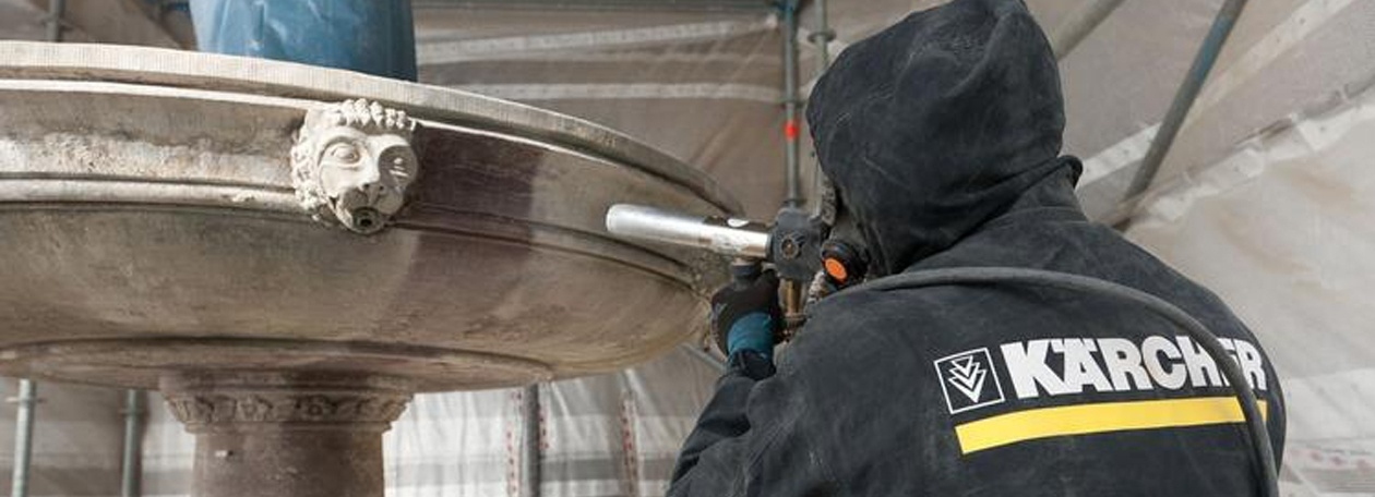 Een Kärcher-technicus verwijdert kalkafzettingen van de middelste kom van de bron in het klooster van Maulbronn met een straalpistool.