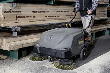 Persoon gebruikt handgeleide veegmachine om schoon te maken