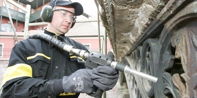 Een Kärcher-specialist verwijdert oude verflagen van de gietijzeren brug in Sibiu met een droogijsstraalapparaat.