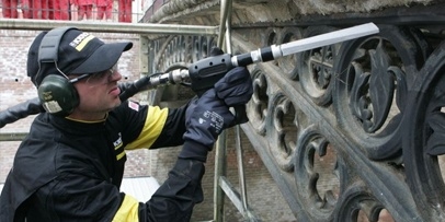 Een Kärcher-specialist reinigt de ronde gietijzeren ornamenten van de brug in Sibiu met een droogijspistool.