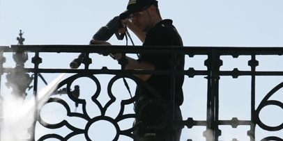 Een Kärcher-medewerker reinigt van bovenaf de details van de gietijzeren balustrade op de brug in Sibiu.