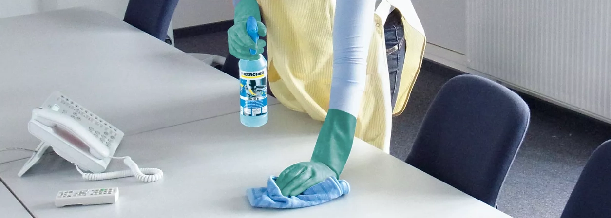 Bureau schoonmaken Persoon maakt bureau schoon met een doek
