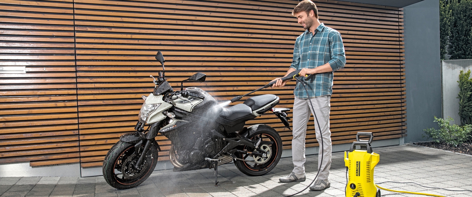 Je motor schoonmaken Man reinigt zijn motor met een Kärcher hogedrukreiniger