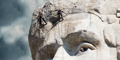 Twee klimmers reinigen secuur de rotsen rond het oog van het beeld van Abraham Lincoln.