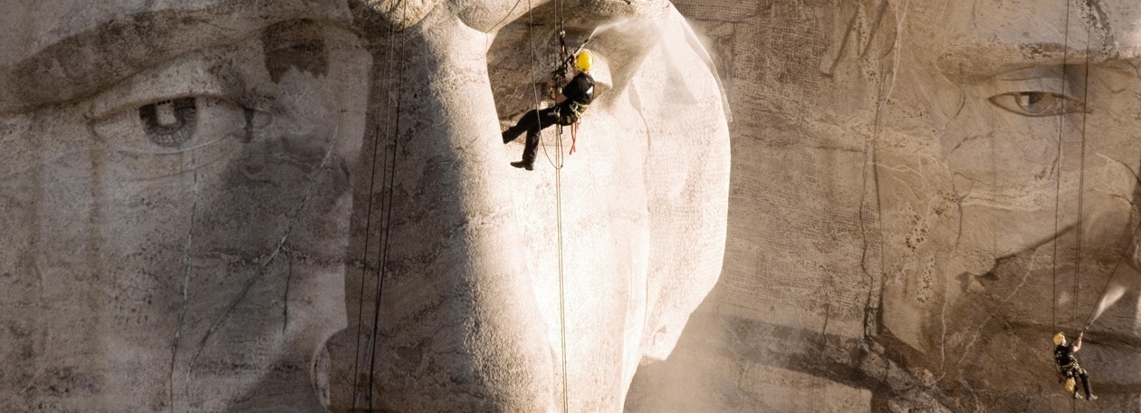 Een industriële klimmer van Kärcher hangt aan touwen bij het gelaat van Abraham Lincoln op Mount Rushmore.
