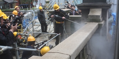 Voorreiniging en naspoelen met warmwater-hogedrukreinigers bij 100 °C Kärcher-technici reinigen de leuning van de brug met stoom terwijl fotografen het proces vastleggen.