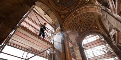 Stellingwerk en gedetailleerde schoonmaakwerkzaamheden binnen in het historische theater Een restaurateur op een steiger reinigt de gewelfde plafonds en elementen in het Praags Nationaal Theater.