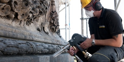 Nauwkeurig droogstralen met calciummagnesiumcarbonaat om de gevel niet te beschadigen Een restaurateur bewerkt de zandstenen sierlijst van het theater in Praag met een fijne Kärcher-deeltjesstraalmethode.