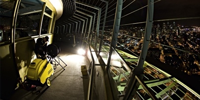 Opstelling van elektrisch aangedreven warmwater-hogedrukreinigers op het torenplatform voor de nachtploeg Een gele Kärcher-hogedrukreiniger op het observatiedek van de Space Needle 's nachts met zicht op de verlichte stad Seattle.