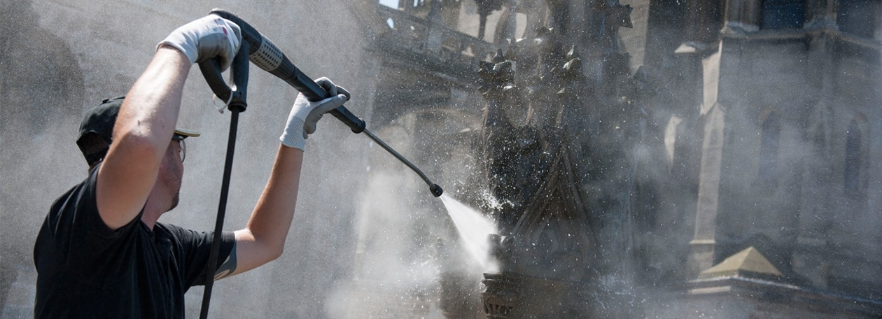 Een Kärcher-technicus voert een proefreiniging uit op de ornamenten van een historisch monument.