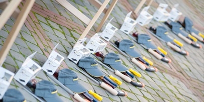 Rijen met Kärcher-petten, veiligheidsbrillen en gereedschap uitgestald voor de deelnemende jongeren op het terrein.