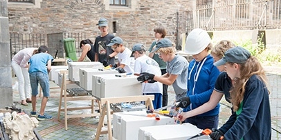 Jongeren werken actief in een workshop aan werktafels buiten tijdens het educatieve project.
