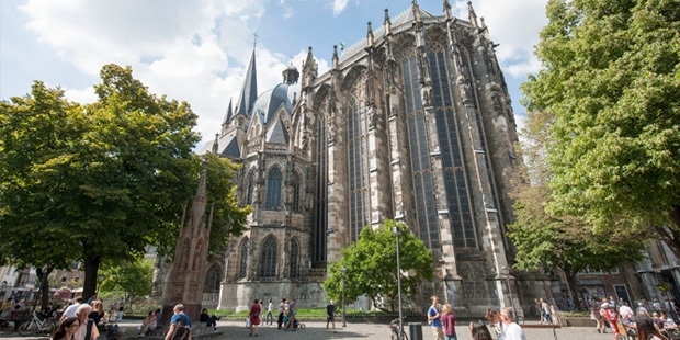 De buitenzijde van de Dom van Aken, met de bekroonde Karls- und Hubertuskapelle badend in het zonlicht.