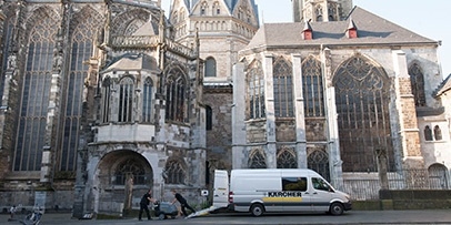 Een Kärcher-servicebus staat geparkeerd voor de historische Dom van Aken ter voorbereiding op testreinigingen.