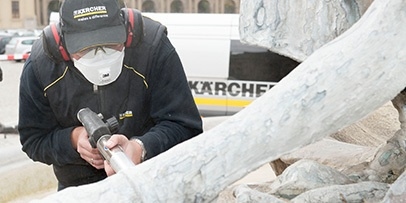 Een Kärcher-technicus met stofmasker voert een nauwkeurige testreiniging uit op de marmeren beelden van de Frankoniabrunnen.