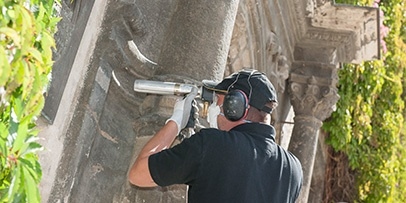 Een Kärcher-technicus voert een precisietestreiniging uit met een lagedrukstraalpistool bij het portaal van het stadhuis van Quedlinburg.