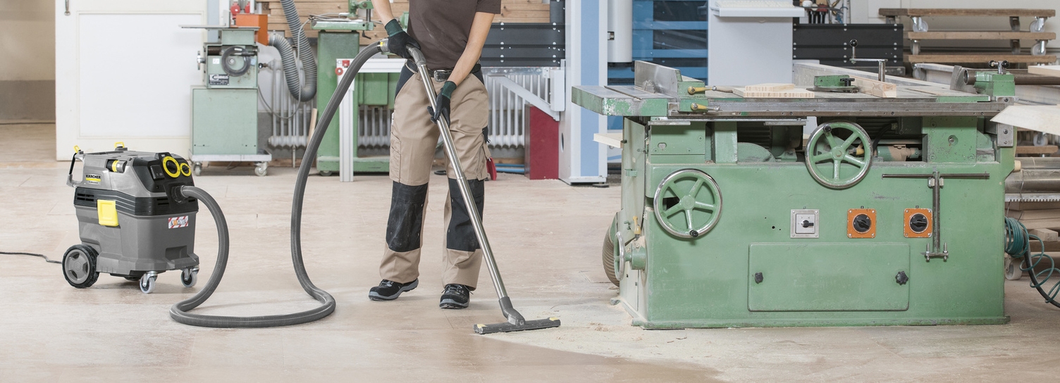 Een persoon stofzuigt een werkplaats