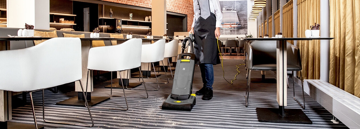 tapijtborstelzuiger restaurant Persoon gebruikt tapijtborstelzuiger om restaurant schoon te maken