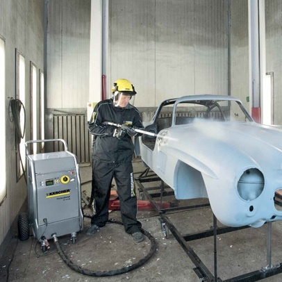 Een Kärcher droogijsreiniger wordt in een werkplaats gebruikt om een autocarrosserie te reinigen