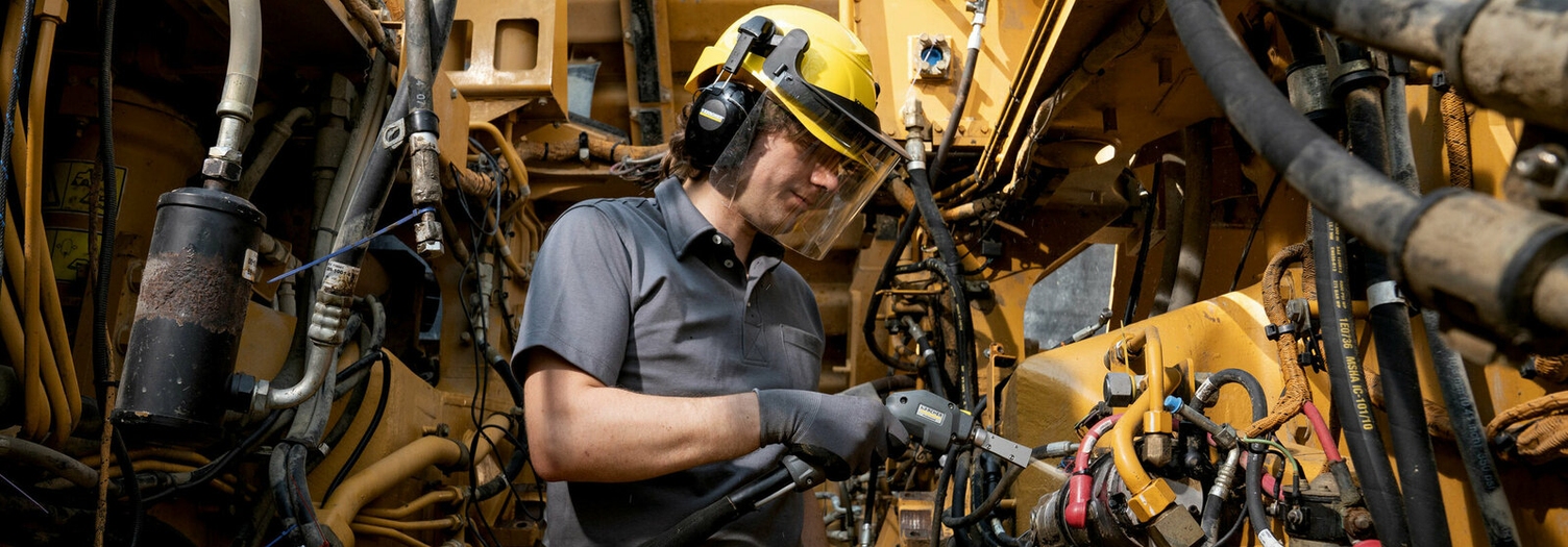 Een persoon reinigt de binnenkant van een bouwmachine met een Kärcher droogijsreiniger