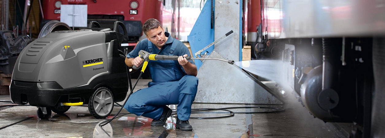 Man maakt werkplaats schoon met warmwater hogedrukreiniger