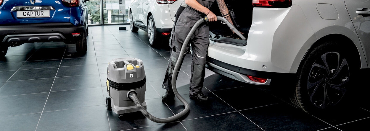 water- en stofzuiger AP-klasse Vrouw maakt auto schoon met stofzuiger in showroom