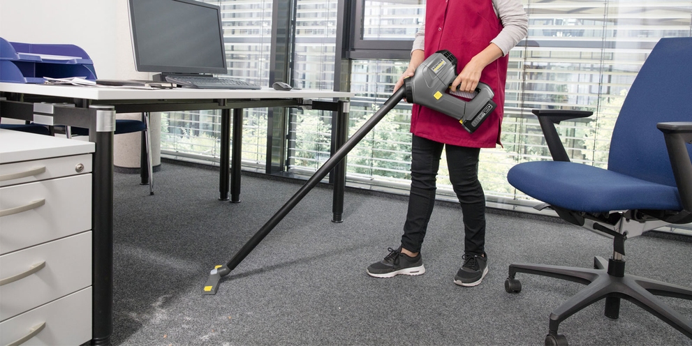 Professionele reiniging van een kantoortapijt met een handige Kärcher steelstofzuiger op accu