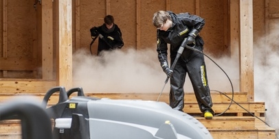 Een Kärcher-medewerker reinigt de houten banken en trappen met een warmwater-hogedrukreiniger.