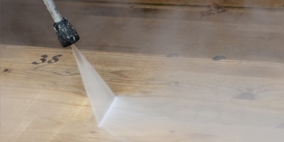Close-up van de waterstraal van een Kärcher-hogedrukreiniger op de houten vloer van het theater.