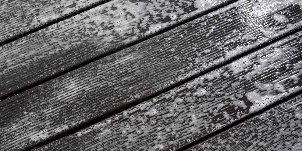 Een houten terras schoonmaken met een reinigingsproduct Een houten terras bedekt met mos