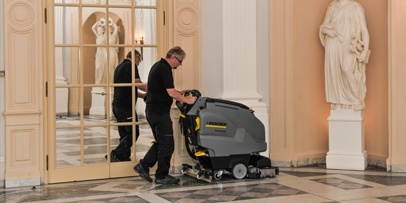 Polijsten met diamantschijven om de natuurlijke glans van het marmer te herstellen Een medewerker bedient de schrobzuigmachine langs de witte zuilen van de historische zaal.