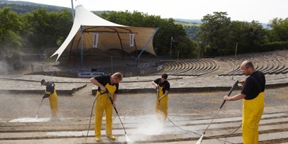 Reinigen van de toeschouwerplaatsen en trappen met krachtige powersproeiers Kärcher-specialisten reinigen de stoelrijen van het Loreley-openluchttheater met het podium op de achtergrond.