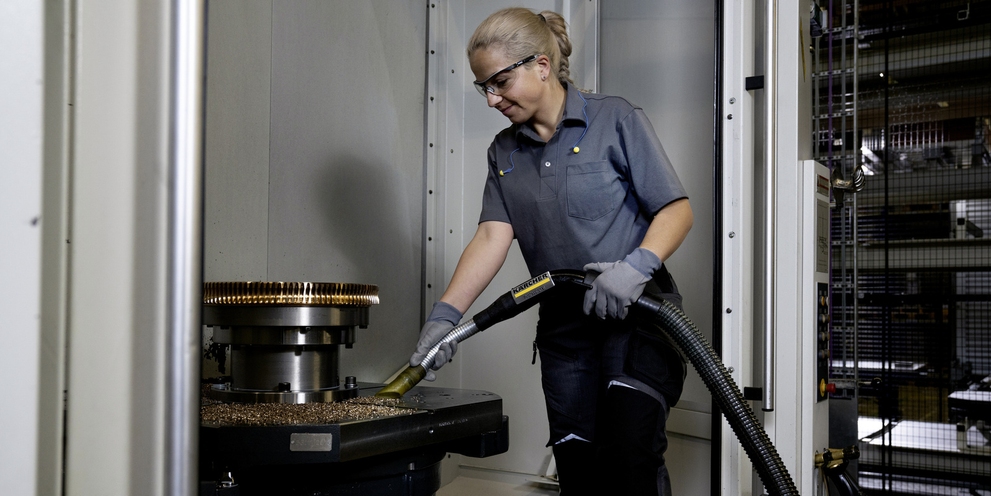 Een persoon zuigt metaalspanen van een machine op