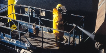 Verwijdering van verflagen en roest met de Fassaden Clean Trailer bij een druk van 5 bar Een Kärcher-technicus in gele beschermkleding spuit een brugpijler van de Princes Bridge schoon vanuit een hoogwerker.